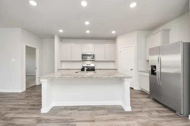 a kitchen with stainless steel appliances granite countertop a refrigerator a sink and a stove