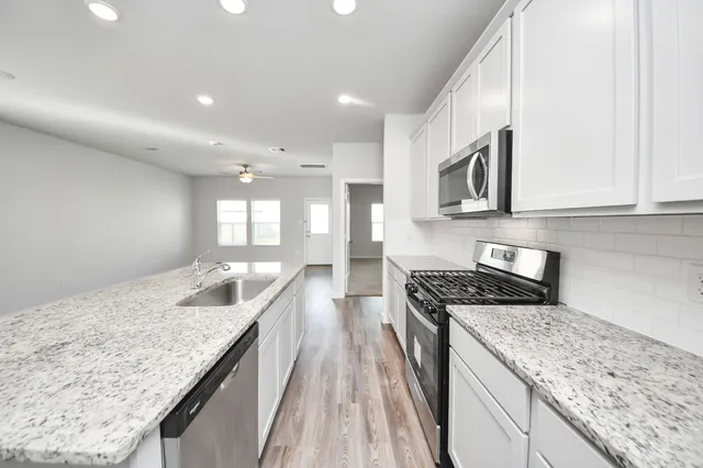 a kitchen with granite countertop kitchen island stainless steel appliances a stove sink and cabinets