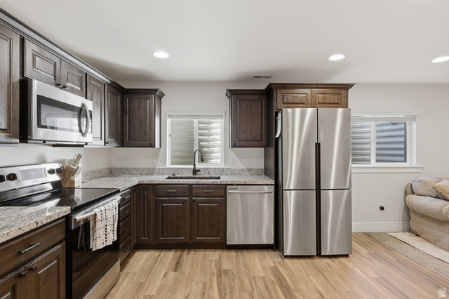 10676 Urban Rdg Cove South Jordan, UT 84095 - Photo 15 of 48 Kitchen featuring dark wood-finish cabinetry, light-toned countertops, stainless steel appliances, and wood-finish flooring