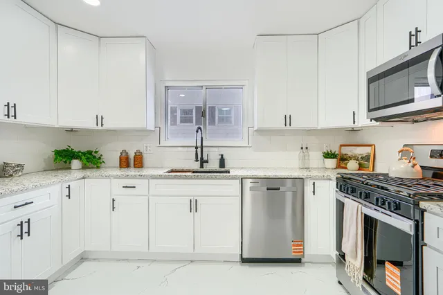 a kitchen with stainless steel appliances granite countertop a stove a sink and white cabinets