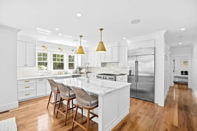 a kitchen with stainless steel appliances a dining table chairs stove refrigerator and cabinets
