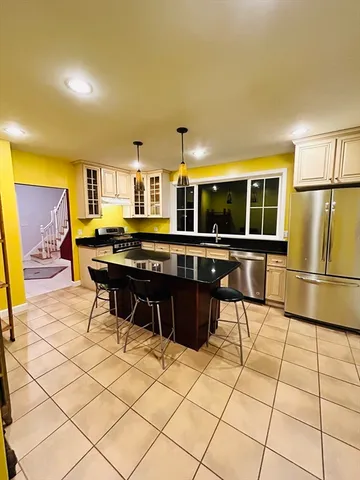 a kitchen with stainless steel appliances kitchen island granite countertop a refrigerator and a stove top oven