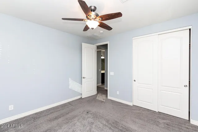an empty room with closet and ceiling fan