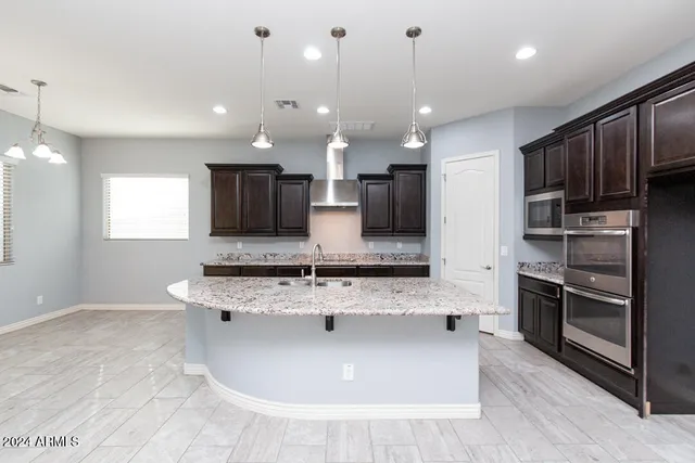 a large kitchen with kitchen island a large counter top stainless steel appliances and cabinets