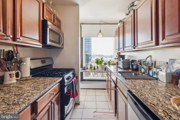 a kitchen with stainless steel appliances granite countertop a stove a sink and a microwave