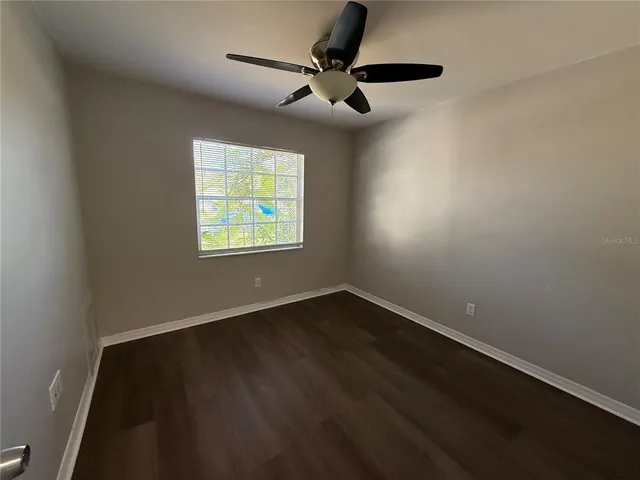 an empty room with wooden floor a ceiling fan and a window
