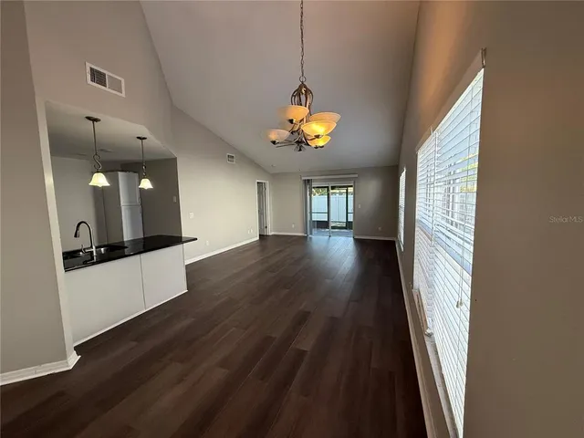 a view of an empty room with a kitchen and wooden floor