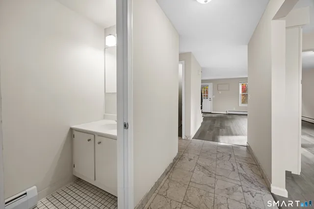 a view of a hallway with wooden floor and a bathroom