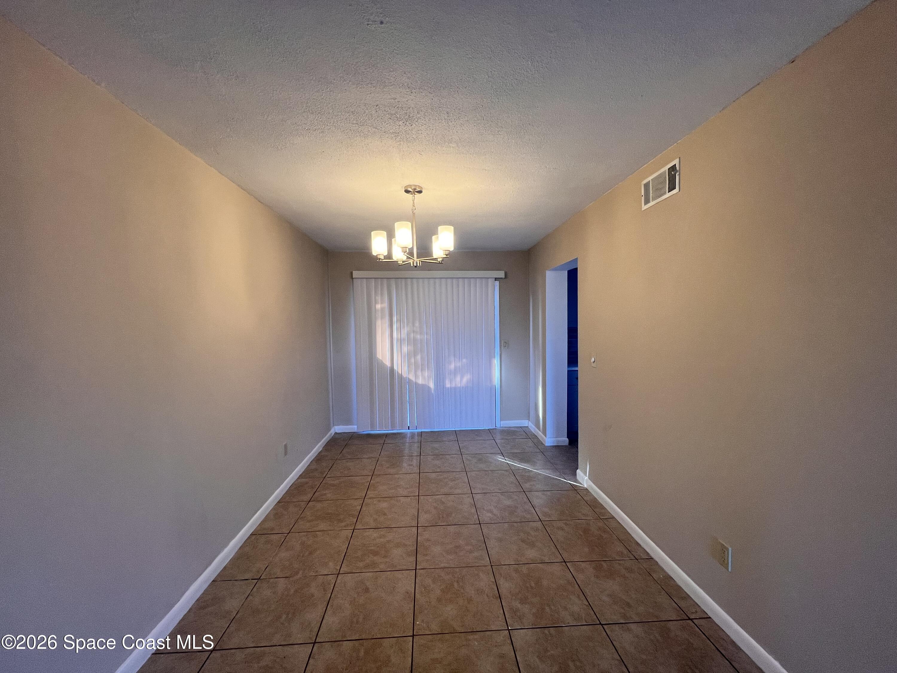4611 Tree Ridge Lane Northeast Palm Bay, FL 32905 - Photo 7 of 19 en empty room with windows and chandelier fan