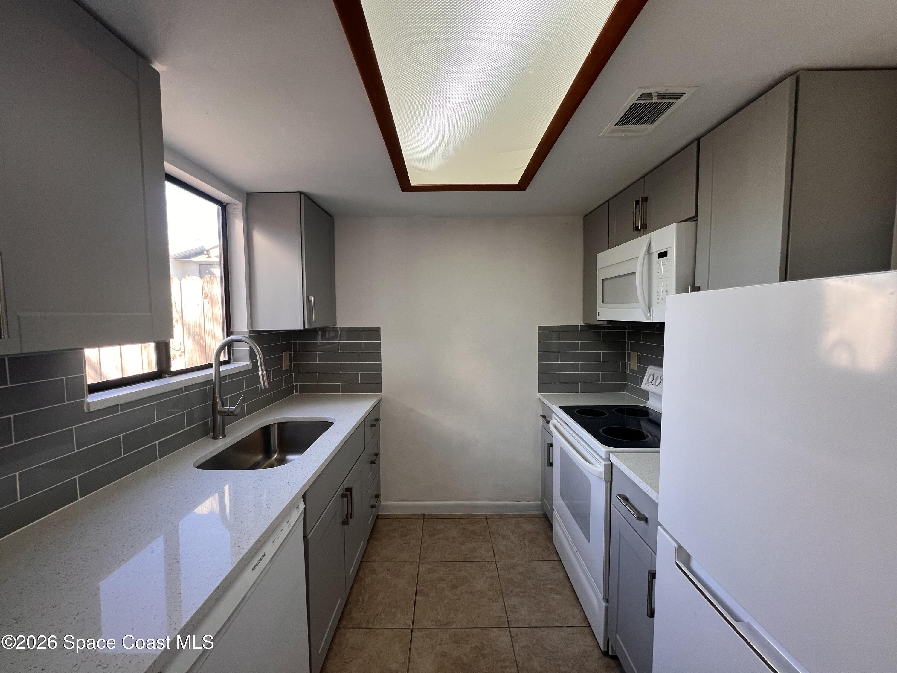 4611 Tree Ridge Lane Northeast Palm Bay, FL 32905 - Photo 10 of 19 a kitchen with stainless steel appliances granite countertop a sink and a stove