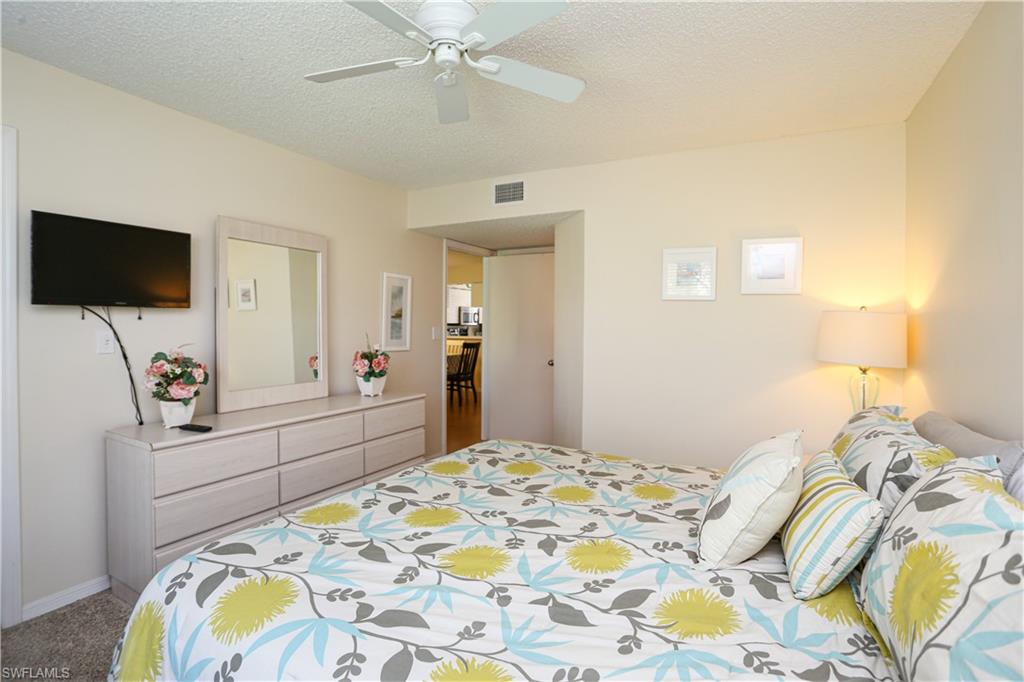287 Quail Forest Boulevard, Unit 117 Naples, FL 34105 - Photo 11 of 29 a bedroom with a bed and a flat screen tv