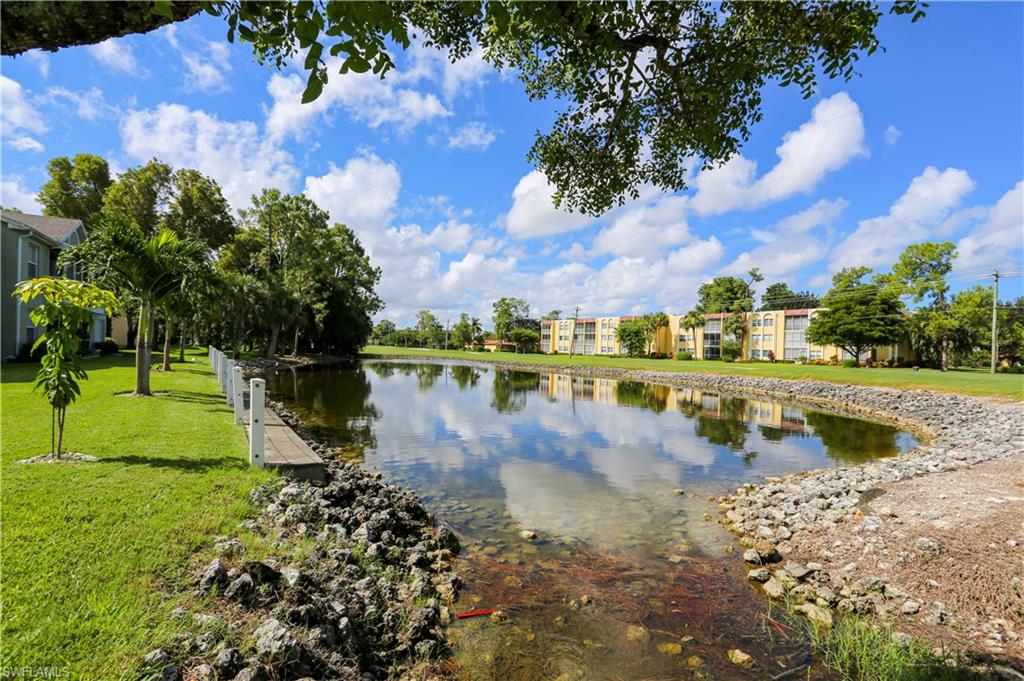 287 Quail Forest Boulevard, Unit 117 Naples, FL 34105 - Photo 27 of 29 a view of a lake with houses in the background