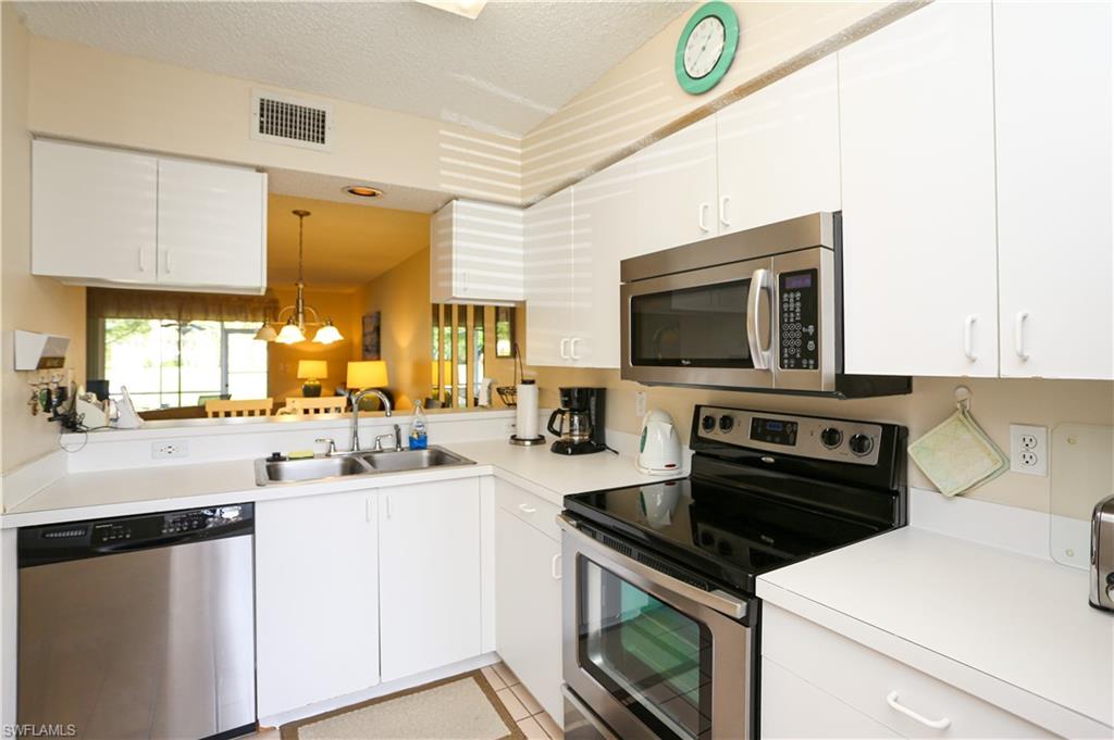 287 Quail Forest Boulevard, Unit 117 Naples, FL 34105 - Photo 3 of 29 a kitchen with a sink a stove and cabinets