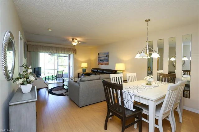 a view of a dining room and livingroom with furniture wooden floor a chandelier