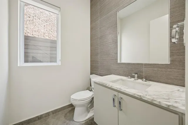 a bathroom with a granite countertop toilet a sink and a mirror
