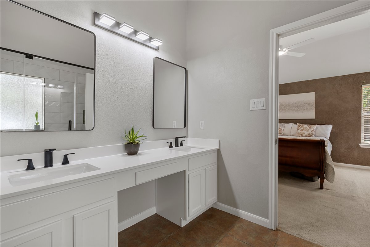 9012 Meacham Way Austin, TX 78749 - Photo 18 of 34 Contemporary bathroom featuring a dual vanity with white cabinetry and countertops, matte black hardware, and rectangular mirrors