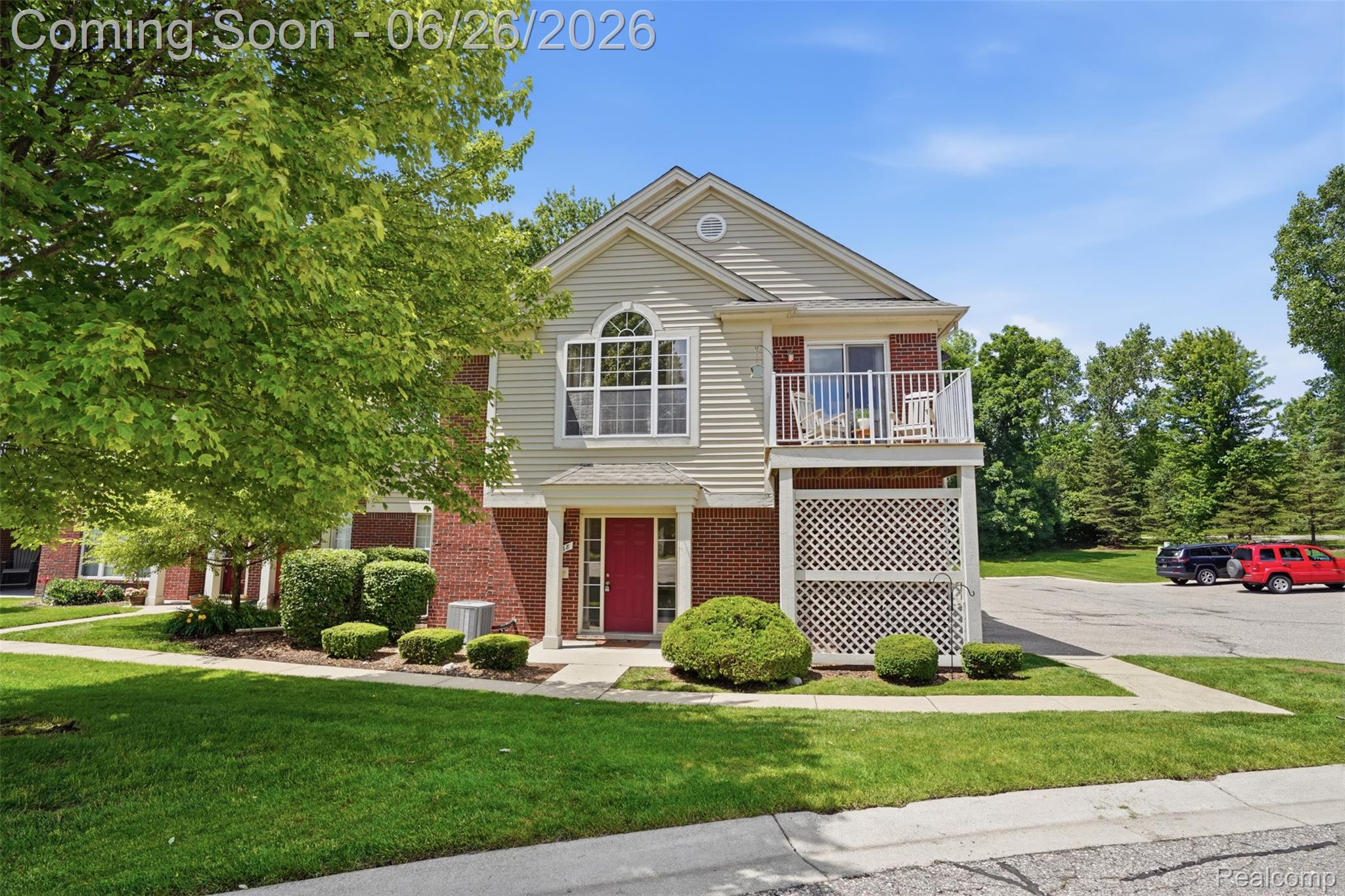 1668 Deepwood Circle Rochester, MI 48307 - Photo 27 of 27 Two-story residence featuring brick and siding facade, a prominent red entry door, an upper-level balcony, an arched window, and a neatly manicured lawn
