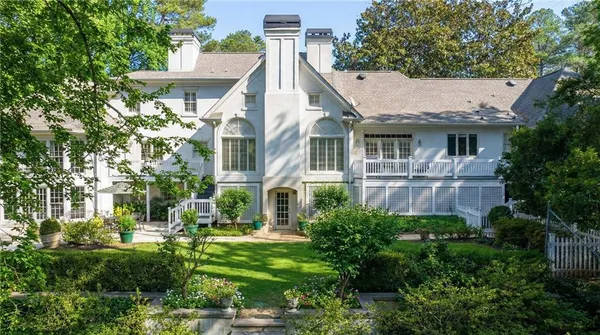 a view of a white house next to a yard with plants and trees