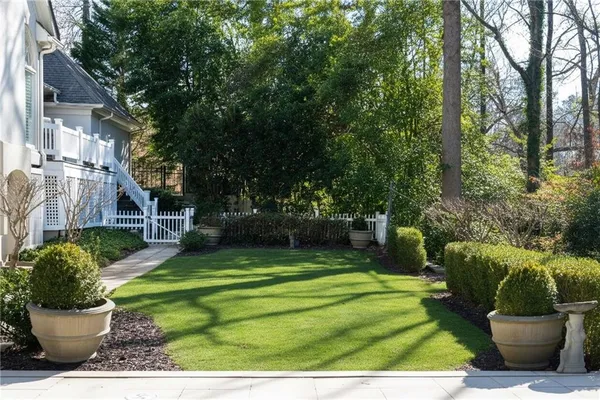 a view of a white house with a yard and a fountain