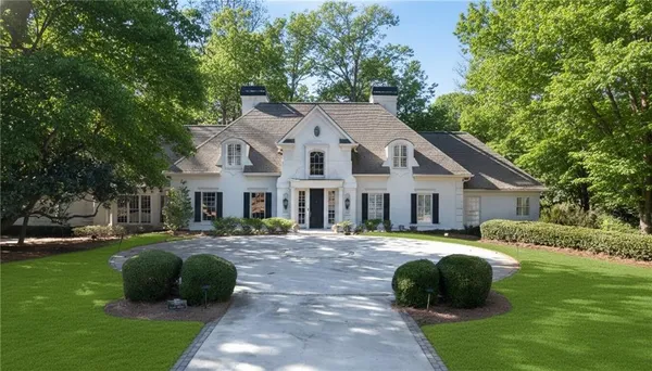 a front view of a house with a garden and trees