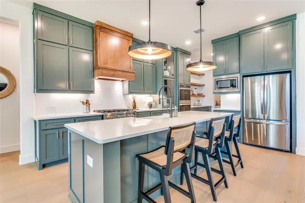 a kitchen with stainless steel appliances granite countertop a sink a refrigerator and a refrigerator