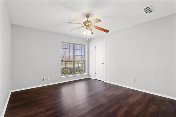 a view of an empty room with window and wooden floor