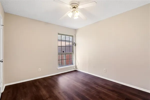an empty room with wooden floor chandelier fan and windows