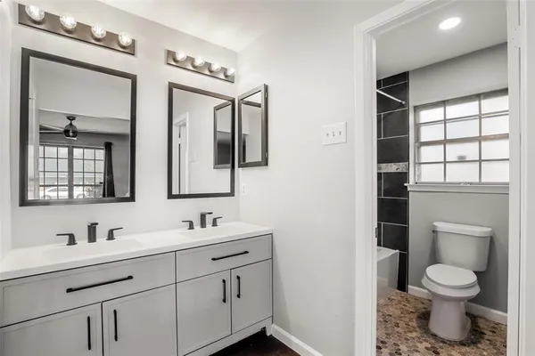 a bathroom with a toilet sink double vanity and mirror