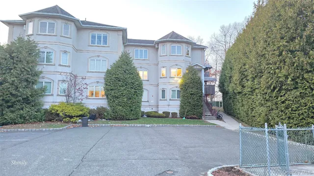 a view of a brick house next to a yard with large trees