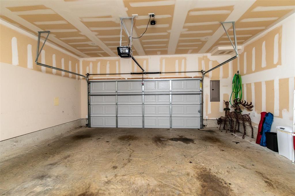 3118 Bedford Road Bedford, TX 76021 - Photo 15 of 29 Spacious garage featuring a sectional garage door, concrete flooring, exposed ceiling joists, and a garage door opener system