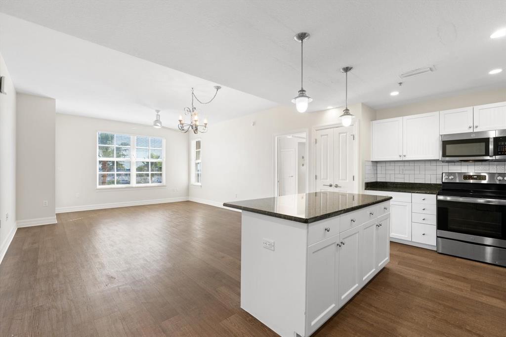 536 Bahia Beach Boulevard, Unit 431C Ruskin, FL 33570 - Photo 3 of 27 a kitchen with kitchen island granite countertop a sink cabinets and wooden floor