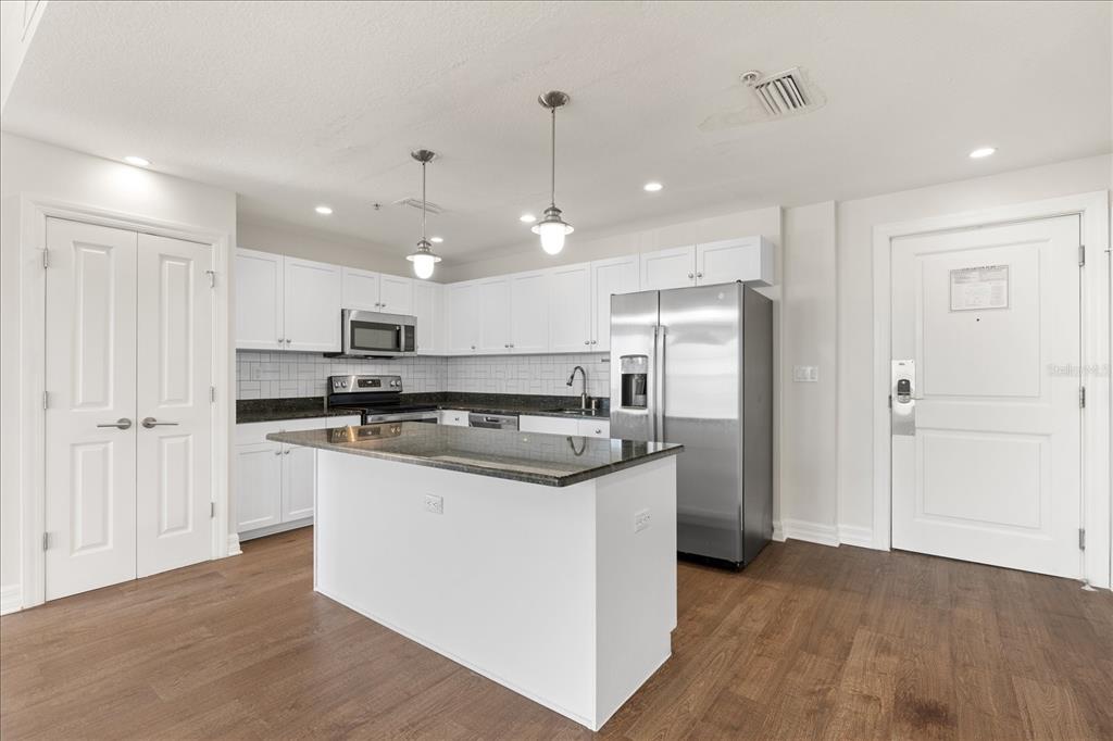536 Bahia Beach Boulevard, Unit 431C Ruskin, FL 33570 - Photo 5 of 27 a kitchen with stainless steel appliances granite countertop a refrigerator a sink dishwasher a stove and white cabinets with wooden floor
