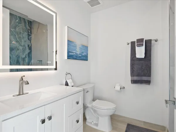 a bathroom with a granite countertop toilet sink and mirror