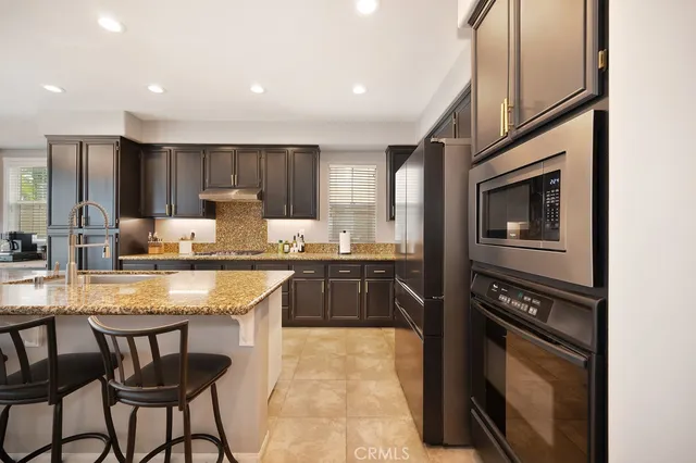 a kitchen with granite countertop a stove refrigerator and a sink