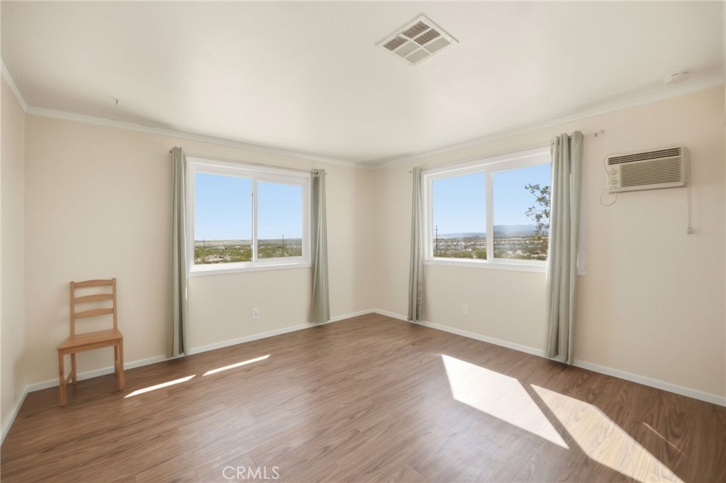 66270 Brant Crossing Road Joshua Tree, CA 92252 - Photo 22 of 46 a view of an empty room with wooden floor and a window