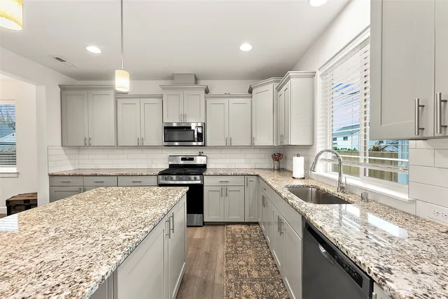 a kitchen with kitchen island granite countertop a stove sink and cabinets