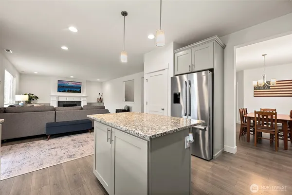 a kitchen with stainless steel appliances granite countertop a refrigerator a sink dishwasher a stove and a refrigerator with wooden floor