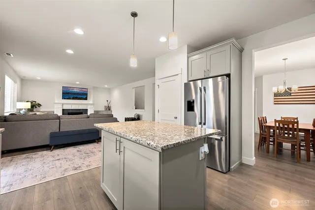 a kitchen with stainless steel appliances granite countertop a refrigerator a sink dishwasher a stove and a refrigerator with wooden floor