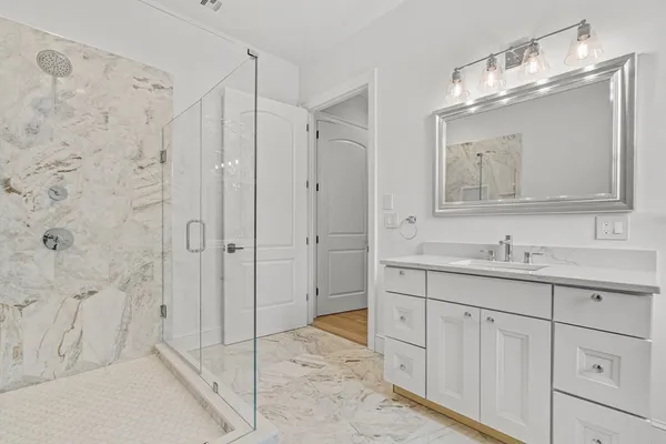 a bathroom with a granite countertop sink a mirror a shower and a bathtub