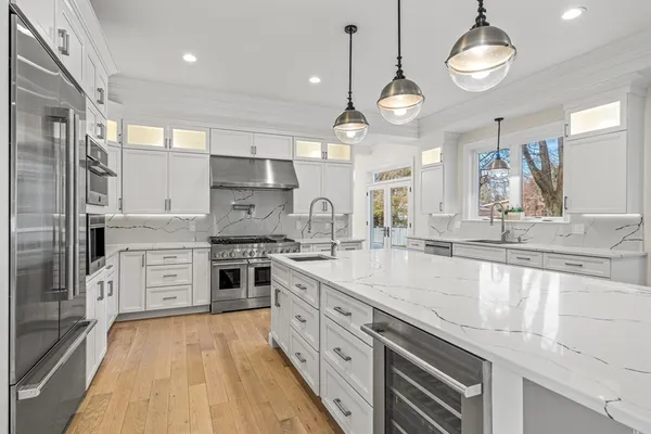 a large kitchen with stainless steel appliances granite countertop a stove oven and a chandelier