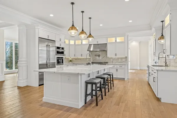 a large kitchen with stainless steel appliances kitchen island granite countertop a large island a stove a sink a dining table and chairs with wooden floor