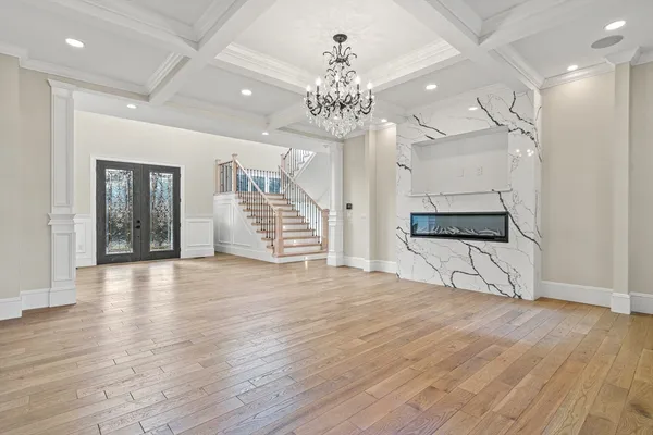 a view of an empty room with wooden floor and a kitchen