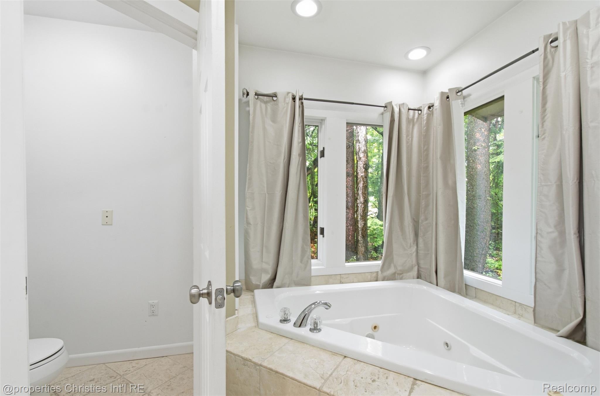 25310 Canterbury Road Franklin, MI 48025 - Photo 22 of 55 Corner soaking tub with tile surround, multiple windows, recessed lighting, and a 2 separate commode areas in first floor Primary Bathroom