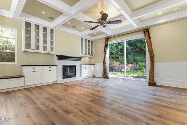 a view of a livingroom with wooden floor a ceiling fan and windows