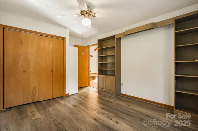 a view of empty room with wooden floor and fan