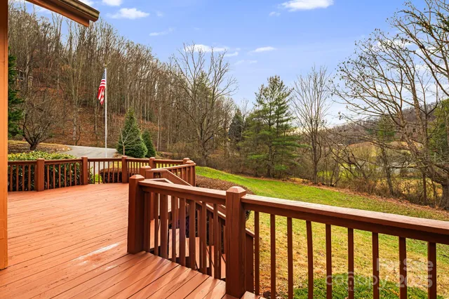 a view of trees and deck with wooden floor and fence