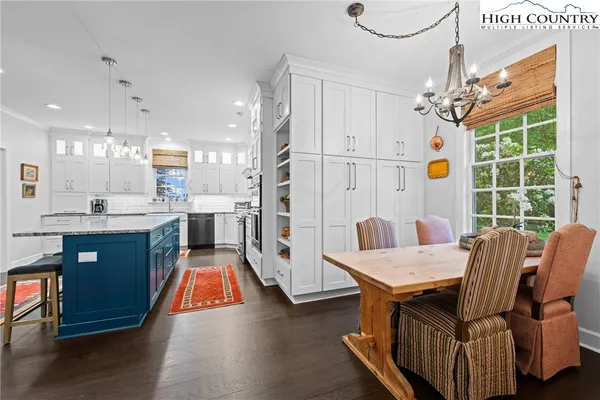 a kitchen with stainless steel appliances granite countertop a stove top oven a sink dishwasher and white cabinets with wooden floor