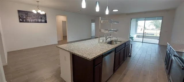 a kitchen with stainless steel appliances granite countertop a refrigerator a sink a stove a microwave and island with wooden floor