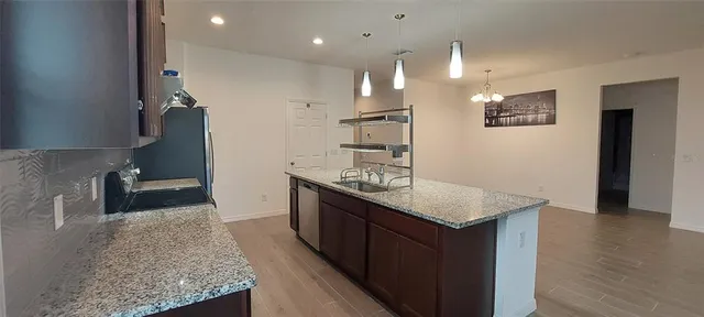 a kitchen with refrigerator a stove a sink and chairs
