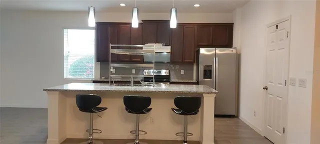 a view of kitchen with stainless steel appliances a refrigerator and wooden floor